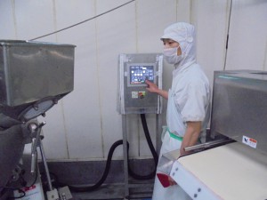 機械の前に立つ作業服の男性の写真